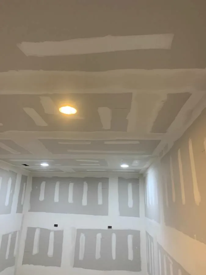 Drywall hung on ceiling and walls, joints visible before taping